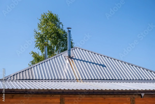 Obraz A thin iron chimney on the roof of the house.