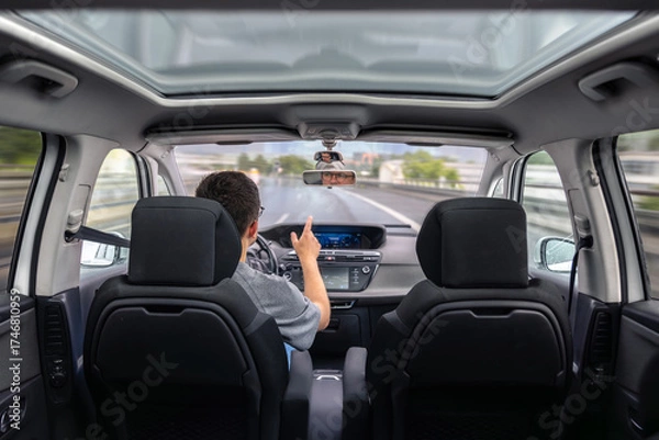 Fototapeta Driver pointing hand while driving. Dynamic motion on highway.