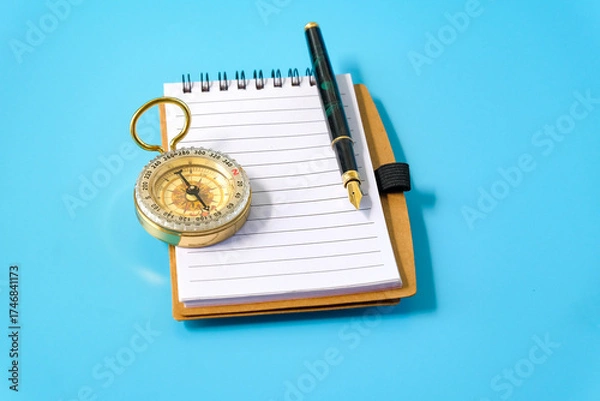 Fototapeta A fountain pen and a brass compass resting on notebook.