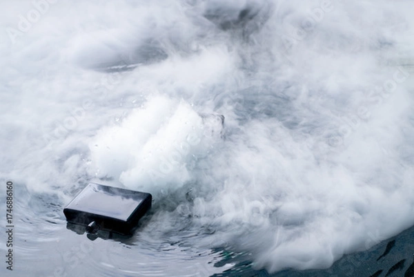 Fototapeta Fog Generator is modern technology device submerged in water with steam and bubbles rising, symbolizing innovation, waterproof design, and durability in extreme environmental conditions.