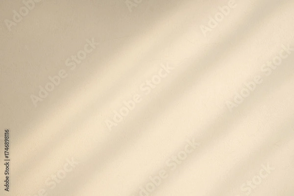 Fototapeta Sunlight creates soft diagonal shadows across a beige wall. The gentle play of light and shadow adds a serene, minimalist touch.AI generated.