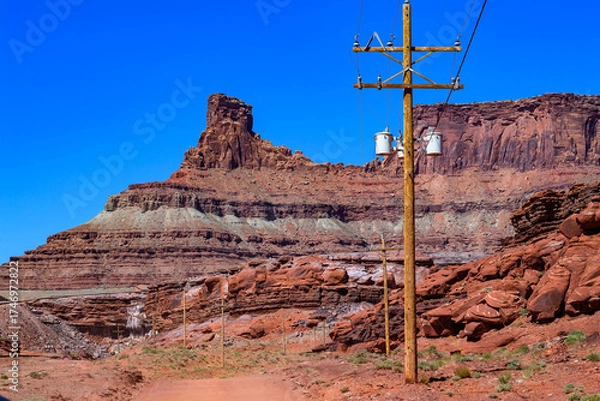 Fototapeta Wooden pole with electric wires on the background of Layered geological formations of red rocks