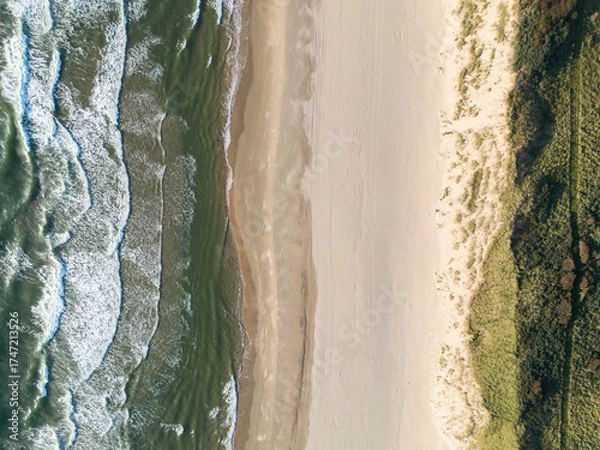 Fototapeta Aerial View of Serene Coastal Beach with Ocean Waves and Grassy Terrain