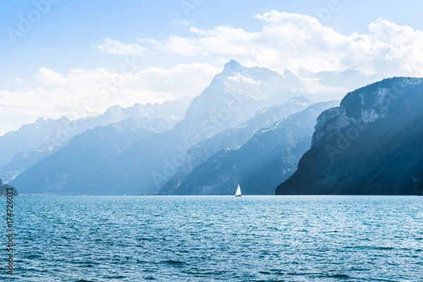 Fototapeta Halftone light and shadow in the mountains. Mountain range. Swiss Alps. Lake Lucerne. White sail on the lake. 