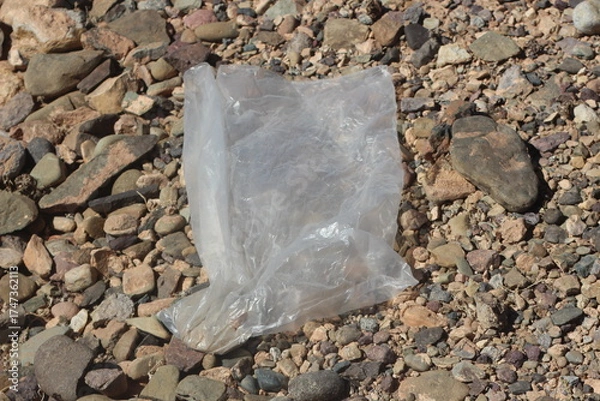 Fototapeta A close up of a transparent plastic bag lying on the ground