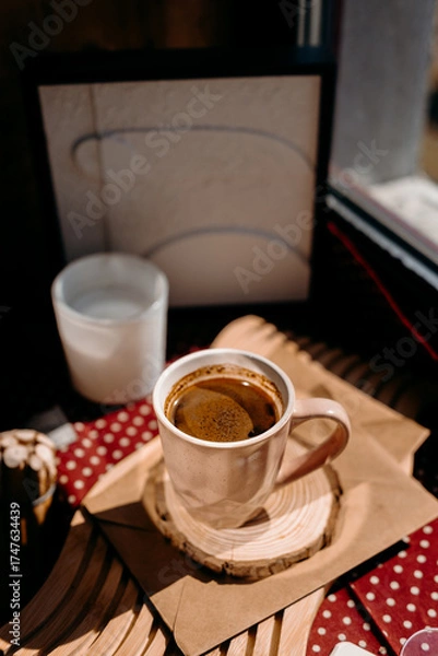 Fototapeta Cozy coffee scene with pink cup, candle and home decor on sunlit windowsill. Warm morning atmosphere.