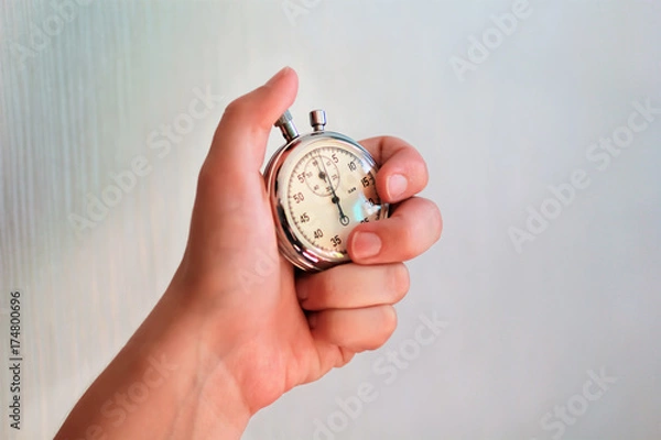 Fototapeta Hand holding a stopwatch and pressing the button to note the time.