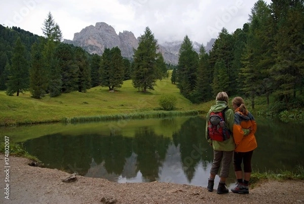 Obraz Mother and child at a small lake on the Seceda High Plateau with a view towards the Geisler mountains, Puez-Geisler National Park, Wolkenstein, Alto Adige, Italy, Europe