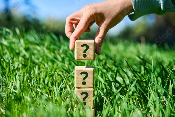 Fototapeta Hand placing wooden cube with question mark symbol on pyramid stack