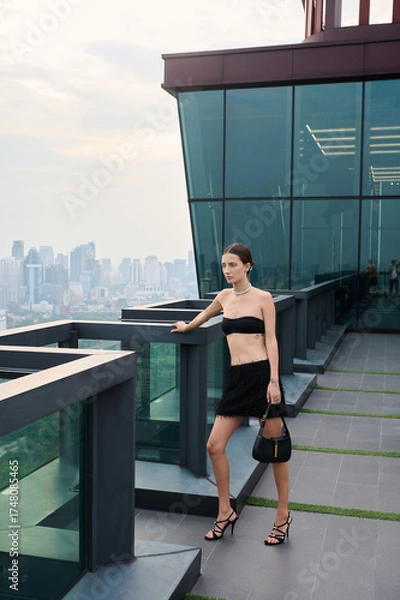 Fototapeta Fashion shoot with a professional model, a girl on the roof of a building in stylish clothes.