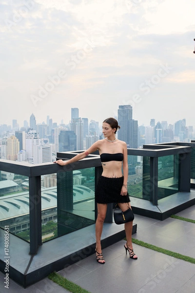 Fototapeta Fashion shoot with a professional model, a girl on the roof of a building in stylish clothes.