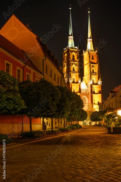 Fototapeta Night view of the Cathedral of St. John the Baptist on Ostrow Tumski in Wroclaw. Warm street lights and calm atmosphere reflect the charm of the city’s historic architecture. Perfect for trave blogs