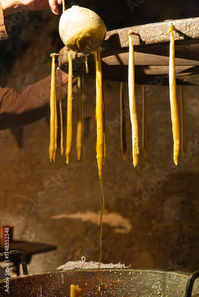 Fototapeta A scene from a historical reenactment where a chandler is making candles using medieval techniques. Warm light fills the rustic workshop, dripping from the wicks.