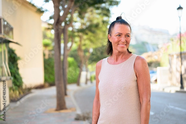 Obraz Portrait of a smiling mature Scandinavian tourist woman walking in the street in Spain