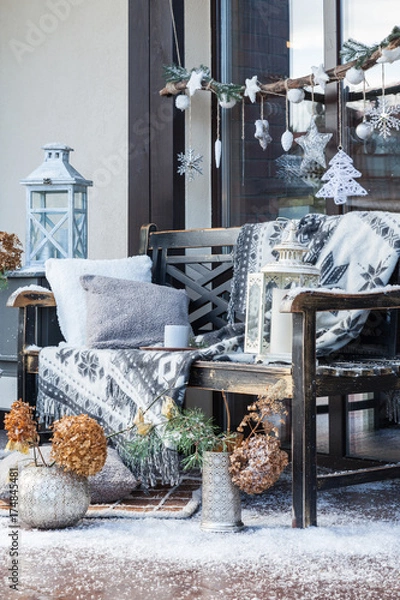 Fototapeta Cozy winter decorations for photo session. Christmas holidays interior. Artificial snow and carpet on the floor. Fir tree decorations, a bench with a gray plaid and a pillow.