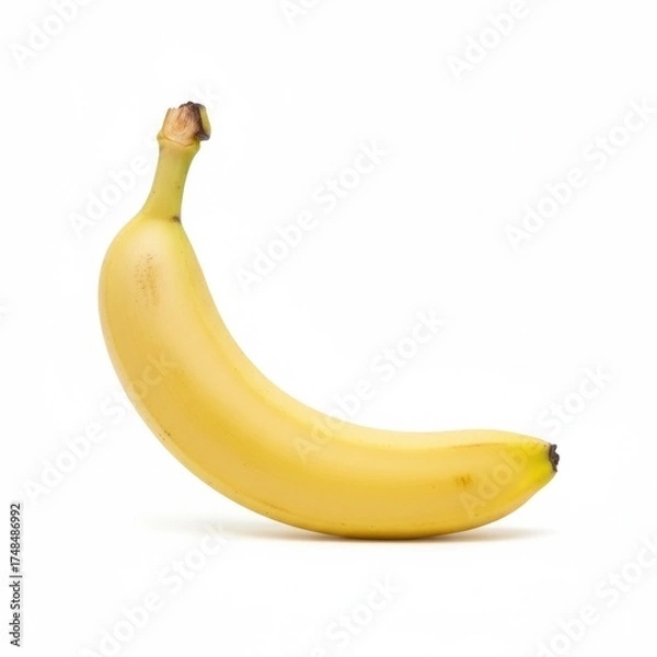 Obraz Single banana isolated on white background, realistic fruit photography with smooth yellow peel and soft natural shadow. Healthy tropical food photo for advertising and design.