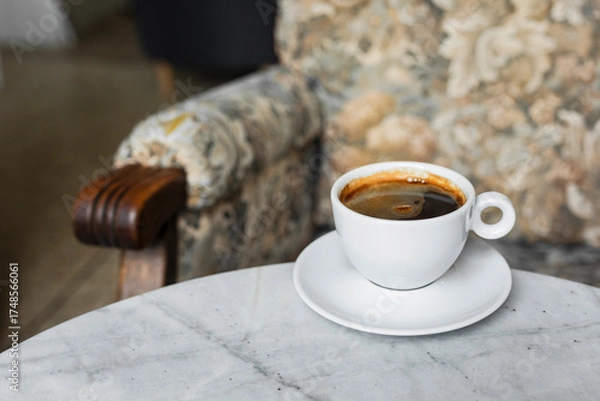 Obraz A white cup of black coffee americano in a cozy atmosphere of a cafe with copy space
