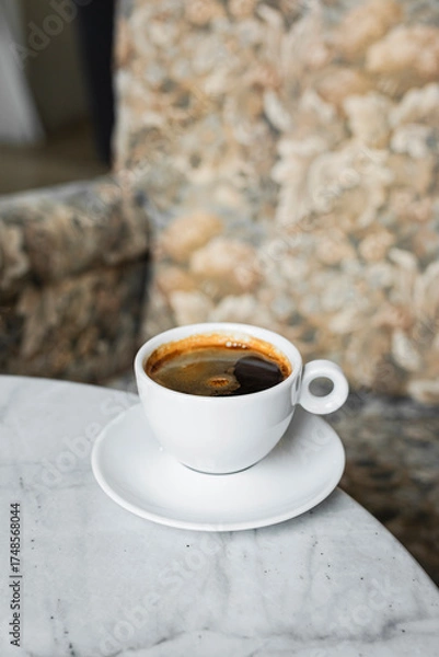 Obraz A white cup of black coffee americano in a cozy atmosphere of a cafe with copy space
