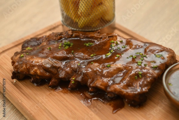 Fototapeta Pork ribs with sauce on a wooden board, close-up
