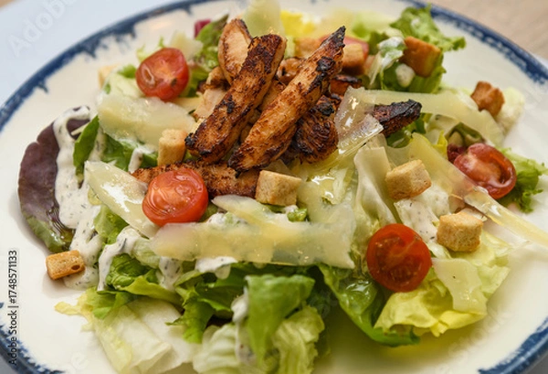 Fototapeta Caesar salad with grilled chicken and cherry tomatoes, close-up