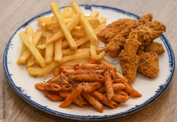 Fototapeta crispy fried chicken strips, French fries, and penne pasta with tomato sauce