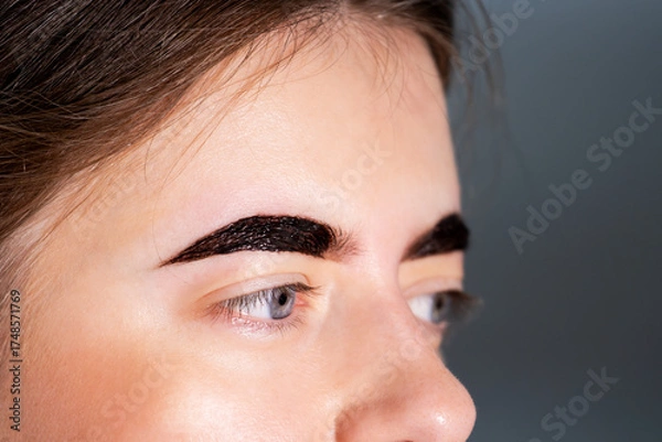 Fototapeta Close-up of Woman's Face with Dark Brown Eyebrow Tint Applied During Styling Procedure
