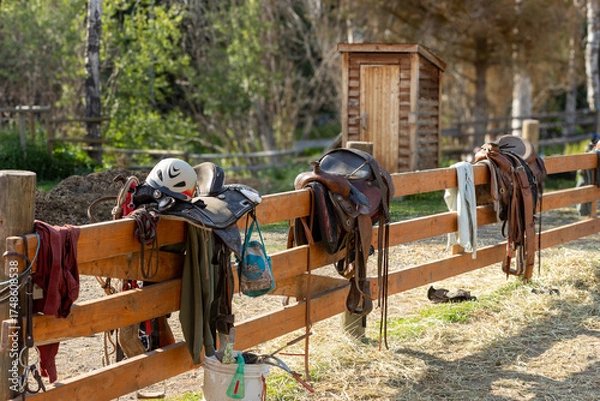 Obraz Horse saddles hanging on a fence at a ranch