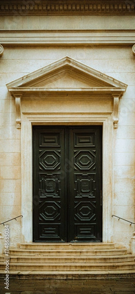 Fototapeta A symmetrical view of a grand, historic stone building featuring elegant wooden double doors. The architectural detail suggests tradition and stability; representing heritage and timeless design.