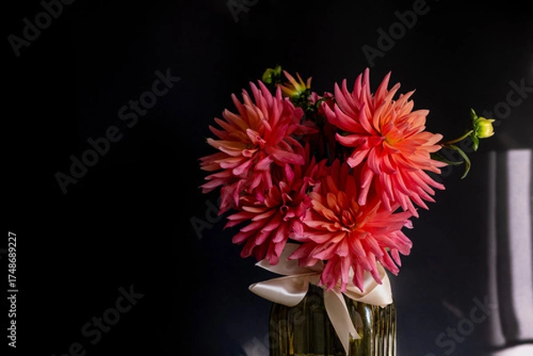 Fototapeta Bouquet of dahlias in green glass vase on dark background with sunlight.Vase of autumn flowers stands on table.Concept: greeting card, autumn holidays. Selective focus. Copy space