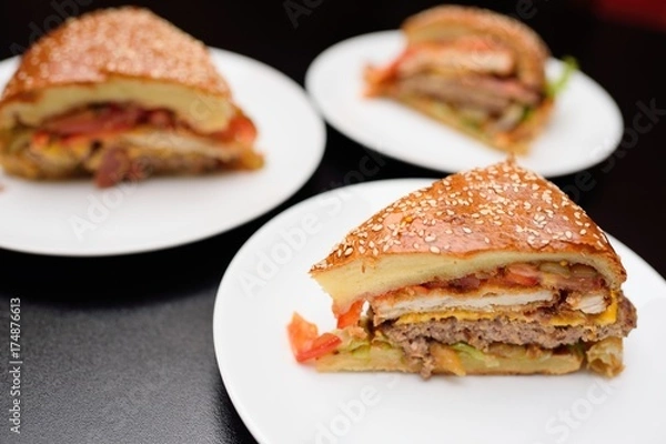 Fototapeta Appetizing slices of a large burger or meat pie closeup.On the table in the restaurant
