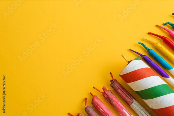 Fototapeta Diagonal composition of a variety of bright, colorful fireworks and firecrackers, leaving ample copy space on a yellow background.