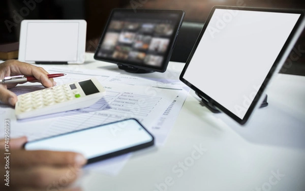 Fototapeta close up shot, hand of businessman calculate cost, profit from e-commerce business working online at home with tablet and mobile phone