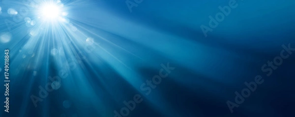 Fototapeta Sunlight rays underwater with blue bokeh and serene glow creating peaceful mood