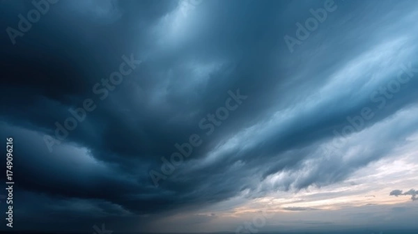 Fototapeta The image depicts a dramatic sky filled with swirling, dark clouds and hints of light at the horizon, creating a moody and atmospheric scene.