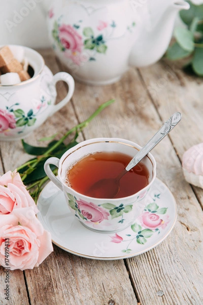 Fototapeta tea set in composition with flowers and marshmallows. Coffee mug on a saucer, a teapot and a sugar bowl. Filmed in the interior