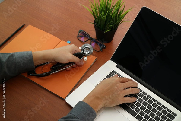 Fototapeta Doctor Working on Laptop with Stethoscope on Desk