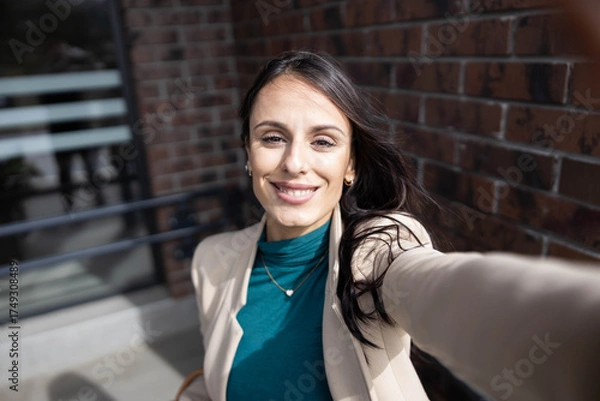 Obraz A joyful woman captures her fun spirit while taking a selfie on a sunny day, radiating confidence and delight.