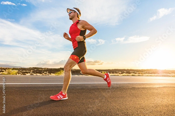 Fototapeta Triathlon - triathlonista biegający w kombinezonie triathlonowym, trening do wyścigu ironman. Mężczyzna biegacz ćwiczeń na Big Island Hawaii. Zachód słońca.