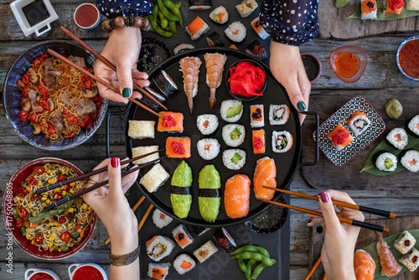 Obraz Japanese sushi rolls like Philadelphia roll, dragon roll and California roll with salmon, crab and calamari, Unrecognizable people enjoying a sushi meal with chopsticks