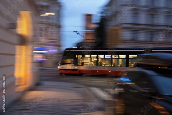 Fototapeta Fast tram and trolley in the city of Prague, Czech Republic, Czechia. Public transport and street at night or late evening. Panning and all image motion blur.