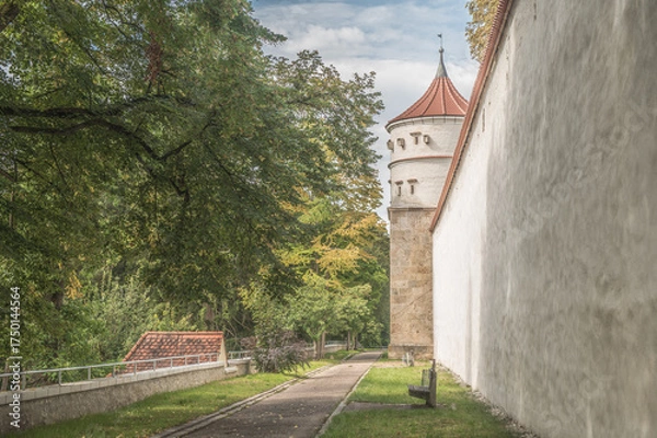 Fototapeta Runder historischer Turm Feilturm an umlaufender Stadtmauer mit überdachtem Wehrgang an Reimlinger Mauer, Mauerpartie mit gepflegter Parkanlage in Nördlingen  vor blauem Himmel mit Wolken