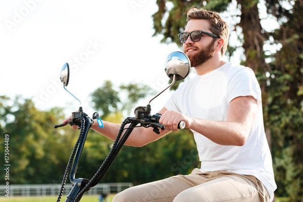 Fototapeta Side view of cheerful berded man in sunglasses