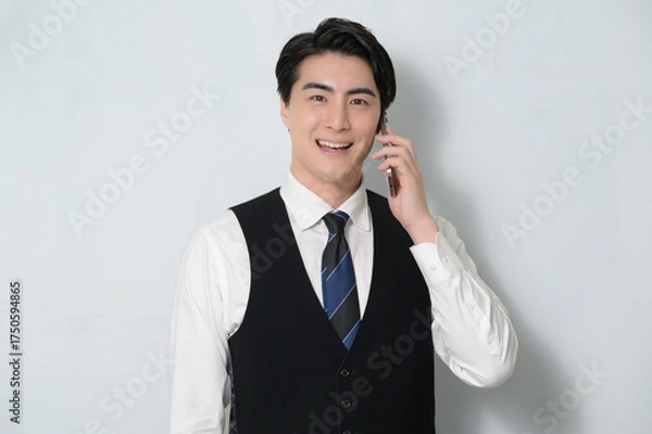 Obraz スマホで通話をするベストを着た日本人男性