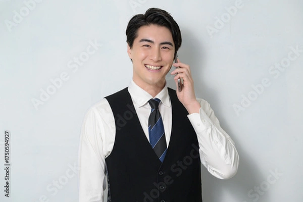 Obraz スマホで通話をするベストを着た日本人男性