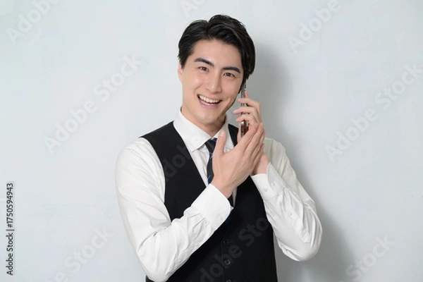 Obraz スマホで通話をするベストを着た日本人男性