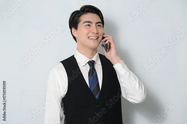 Obraz スマホで通話をするベストを着た日本人男性