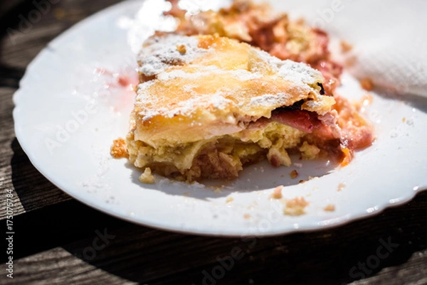 Fototapeta Half eaten cheese and cherry strudel with sugar on top.