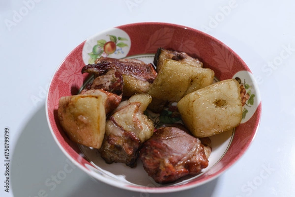 Fototapeta A bowl of traditionally smoked pork, featuring tender chunks of meat with golden, crispy fat layers. The rich brown color shows its slow smoking process, giving it a savory aroma and rustic flavor. 