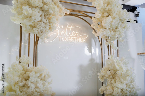 Fototapeta Beautiful floral arch with glowing sign at a celebration event in a modern venue