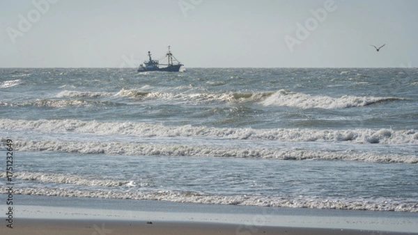 Fototapeta single ship is sailing on the North Sea, ship, sails and waves shine in the evening light, North Sea beach before sunset with waves of the ocean